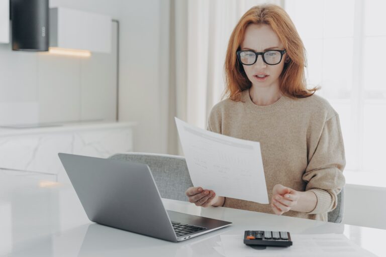 Professional female economist calculates finance at home holds paper document makes financial report